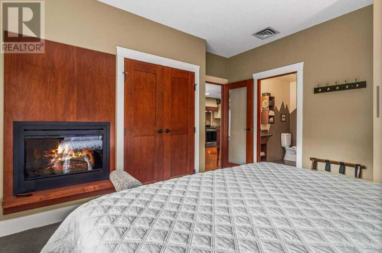 A hotel room with a fireplace, a large bed, and a wooden wardrobe.