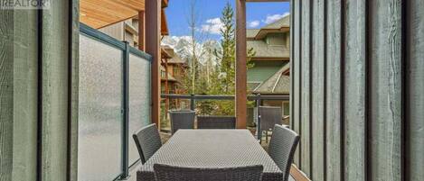 A balcony with a table and chairs, overlooking a mountainous landscape.