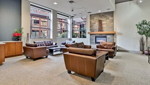 Eine geräumige Lobby mit Ledersofas, einem Kamin, großen Fenstern und einer Wand mit Steinverkleidung.