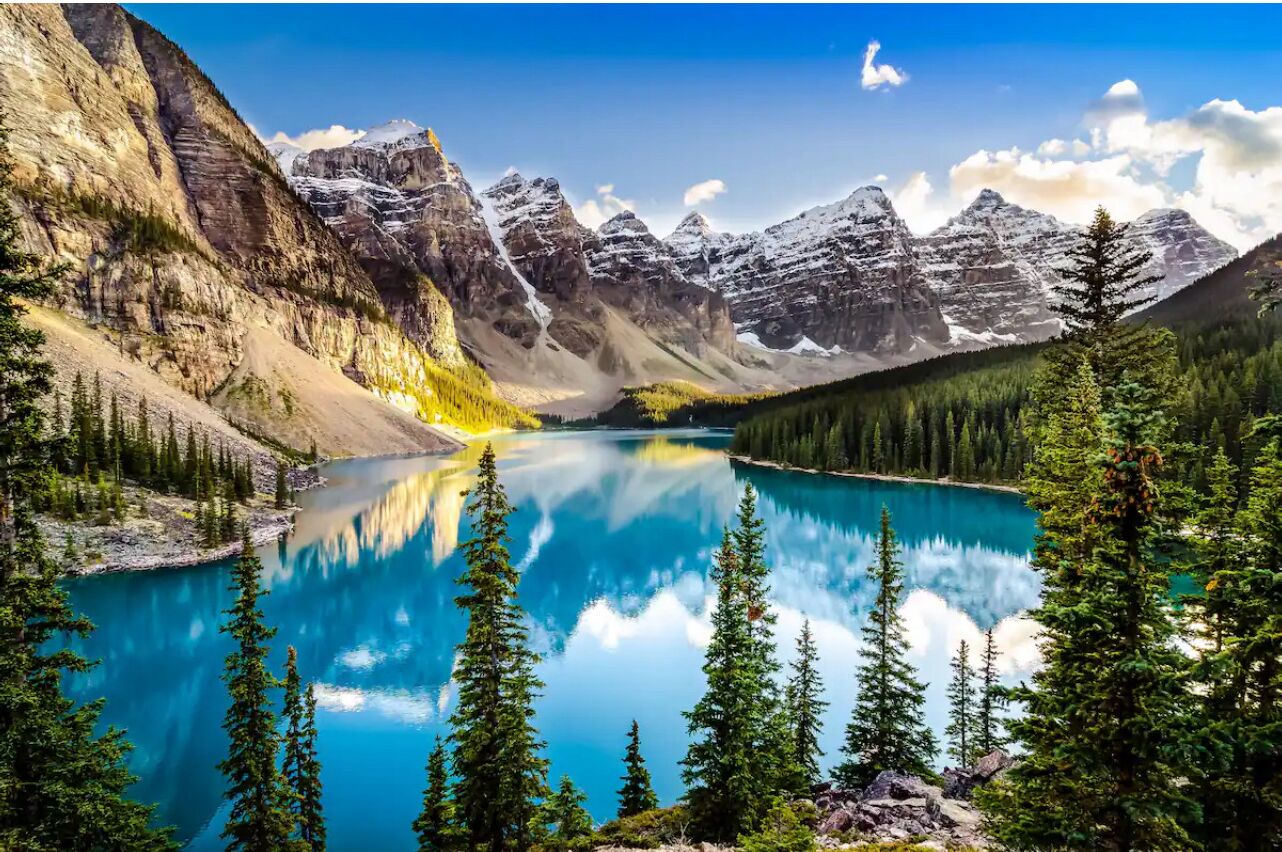 Un lago de montaña con reflejos cristalinos, rodeado de laderas boscosas y cumbres escarpadas.