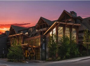A lodge with a prominent wooden facade, large windows, and a sign indicating it is a solar-powered facility. -  top hotel resort 2bd 2bth (Canmore)