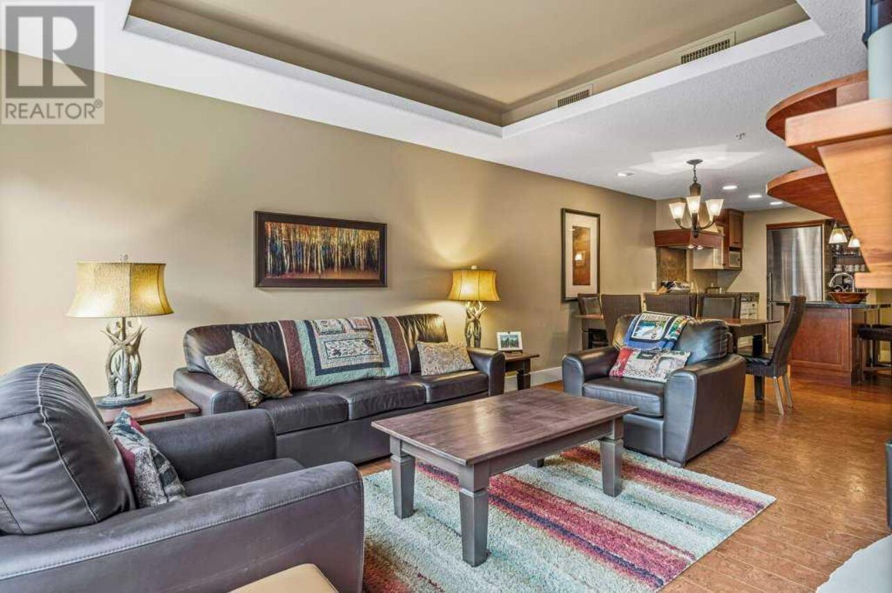 A modern living room with a sofa set, a coffee table, and a dining area with a kitchen in the background.