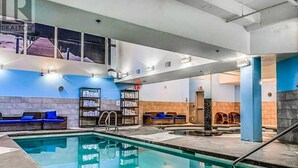 Ein Hallenbad mit freiem Blick auf den Poolbereich, eine Rezeption und Sitzbereiche.