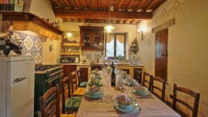 Comedor con mesa de madera lista para una comida, rodeada de sillas.