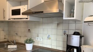 A modern kitchen with a built-in microwave, stainless steel range hood, and a coffee maker. - Appartementencomplex Titisee (Titisee-Neustadt)