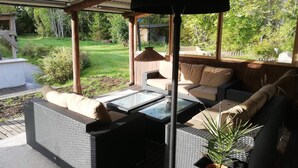 A covered patio with wicker furniture, a glass table, and a potted plant. - 4 Star Holiday Home in Skutskar-by Traum (Alvkarleby)