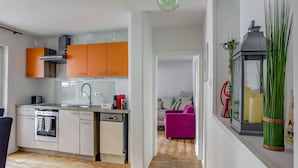Eine moderne Küche mit orangenen Schränken, einer weißen Arbeitsplatte und einem Holzboden.