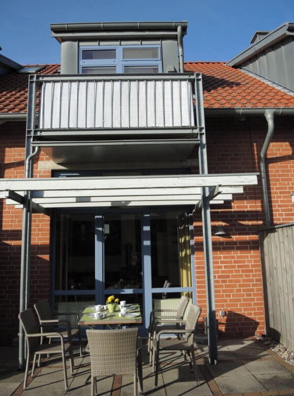 A two-story house with a balcony and a covered patio area. - Charming Apartment in Ostseebad Rerik (Rerik)