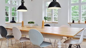Ein Essbereich mit einem Holztisch, sechs Stühlen und zwei schwarzen Pendelleuchten.