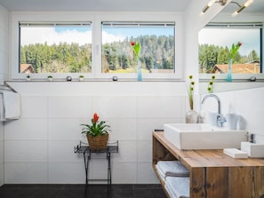 Ein modernes Badezimmer mit großem Fenster, Waschbecken und Holz-Badmöbel.
