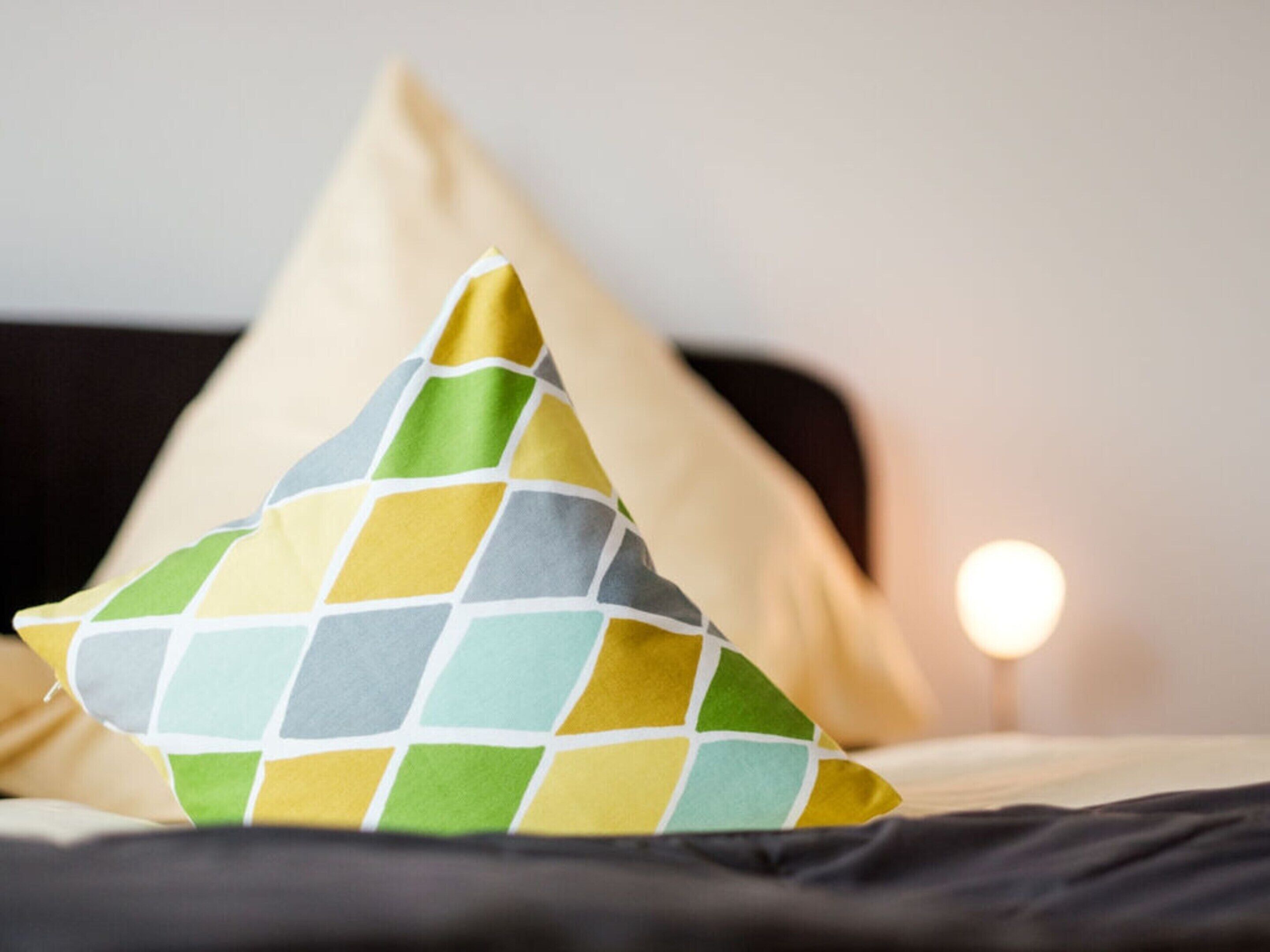 Un lit avec un oreiller orné d’un motif géométrique.
