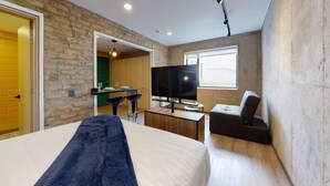 Une chambre d’hôtel moderne dotée d’un grand lit, d’une télévision, d’un bureau avec une chaise et offrant une vue sur la ville.