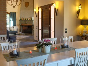A dining area with a long table set for a meal, a fireplace in the background, and wall-mounted lighting.