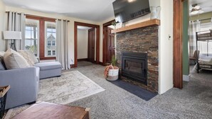 Una sala de estar con chimenea, un sofá, una mesa de centro y un televisor sobre la chimenea.