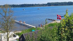 A lakeside view with a dock, boats, and a flag. - 6 Person Holiday Park Home in Hejls (Hejls)