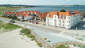 Een groot wit gebouw met rode daken, gelegen aan de weg met uitzicht op een meer.