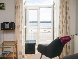 A room with a view of a lake, a chair, a small table, and a radiator.