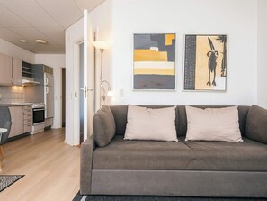 A modern living room with a grey sofa, a kitchen in the background, and two abstract paintings on the wall. - 6 Person Holiday Park Home in Hejls (Hejls)