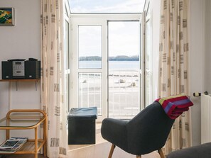 Una habitación con vista a un lago, una silla, una mesita y un radiador.