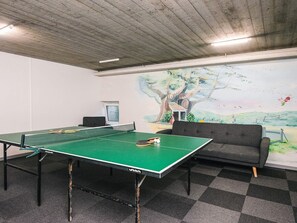 A ping pong table with a net, a sofa, and a mural of a tree and landscape on the wall. - 6 Person Holiday Park Home in Hejls (Hejls)