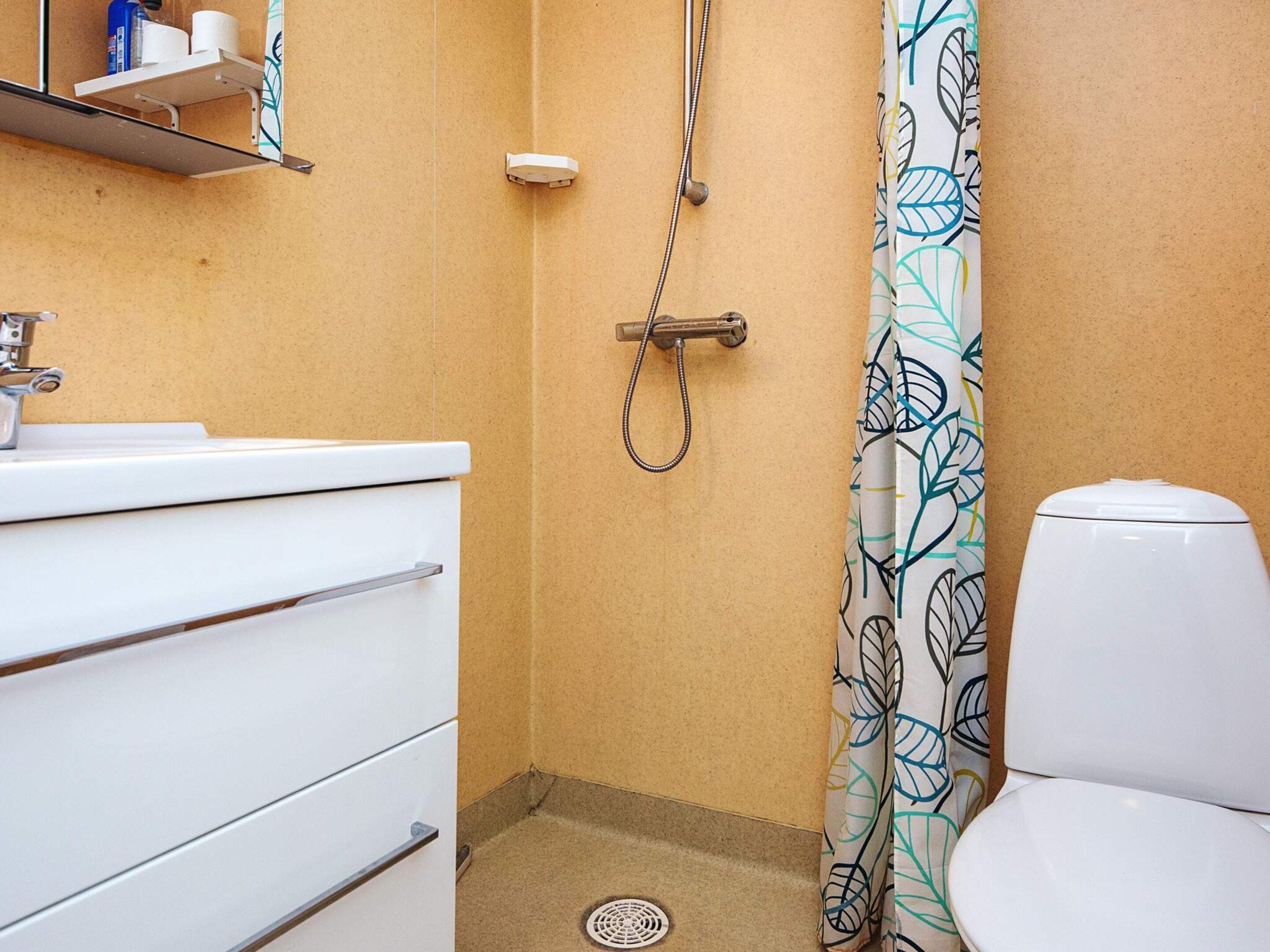 A bathroom with a shower, toilet, and a sink with a mirror above it.
