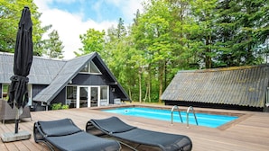 Eine Holzterrasse mit zwei Liegestühlen und einem Pool.