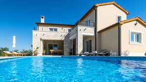 A two-story house with a swimming pool, a balcony, and a patio with lounge chairs. - Patricia Comfortable Holiday Residence (Kanfanar)