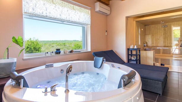 A bathroom with a large bathtub, a window with a view, and a wooden ceiling. - Patricia Comfortable Holiday Residence (Kanfanar)