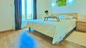 A bedroom with a bed, a bedside table, a nightstand, a window with curtains, and a wall-mounted light fixture. - Patricia Comfortable Holiday Residence (Kanfanar)
