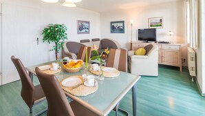 A modern living room with a dining area, a television, and a plant. - Sea View 4 - Villa Bella Vista (Sassnitz)