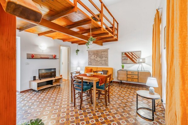 Un coin repas avec une table et des chaises en bois, un téléviseur et un sol à motifs.
