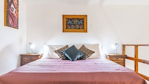 Ein Schlafzimmer mit einem Bett, zwei Nachttischen, einem hölzernen Kopfteil, einem Wandbild und einem Fenster.