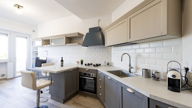 A modern kitchen with grey cabinets, a white countertop, and a built-in oven. - GuestHost - Waterfront Sea View Modern Apartment with Balcony! (Pescara)