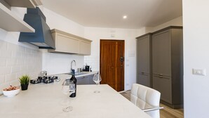 A kitchen with a marble island, a white chair, and a wooden door. - GuestHost - Waterfront Sea View Modern Apartment with Balcony! (Pescara)