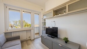 A modern living room with a sofa, TV, and built-in shelves. - GuestHost - Waterfront Sea View Modern Apartment with Balcony! (Pescara)