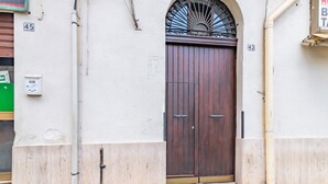 Puerta doble de madera con una reja metálica, los números 45 y 43 en la pared, y una caja de servicios.