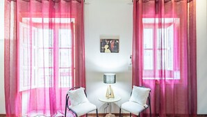 Una habitación con dos sillas, una mesita con una lámpara y un cuadro en la pared.