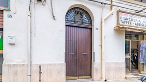 Un edificio con una amplia puerta doble de madera, un pequeño ventanal con reja metálica y un cartel sobre la puerta.
