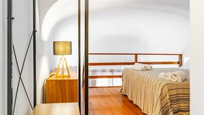 Un dormitorio con una cama, una mesita de noche con lámpara y una ventana.