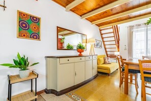 A room with a wooden ceiling, a white cabinet, a yellow sofa, a dining table with chairs, and a ladder. - GuestHost - The Traveller's House - Palermo Lemon Apartment (Palermo)