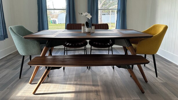 Een eethoek met een houten tafel, vier stoelen en een bank.