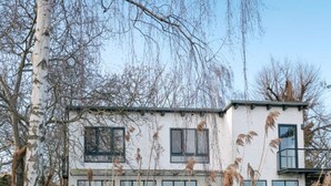 Una casa moderna de dos pisos con ventanas amplias y fachada blanca.