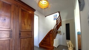 Un escalier en bois menant à un deuxième étage, un radiateur blanc et une armoire en bois.