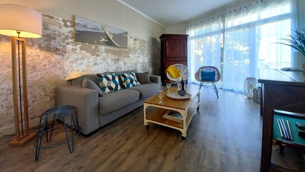 Un salon avec un canapé, une table basse, une lampe et une vue dégagée grâce à de grandes fenêtres.