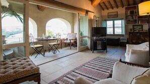 Un salón amplio con un gran ventanal, un televisor y una estantería.