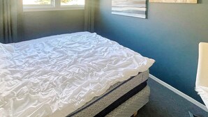 Une chambre à coucher avec un lit, une fenêtre et un tableau accroché au mur.