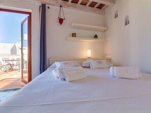 Een hotelkamer met een groot bed, een klein tafeltje, een hanglamp en uitzicht op buiten.