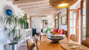 A spacious dining area with a wooden table, chairs, and a decorative bowl centerpiece. - Belvilla by OYO Atico 00 (Tarifa)