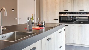 A modern kitchen with a central island, stainless steel appliances, and light wood cabinetry. - Villa With Garden, in a Holiday Park at the Water (Idskenhuizen)