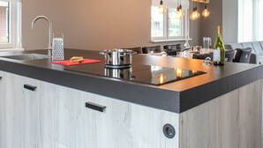A modern kitchen with a large island, stainless steel appliances, and a hanging light fixture. - Villa With Garden, in a Holiday Park at the Water (Idskenhuizen)
